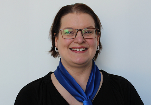 Lächelnde Frau mit Brille und blauem Schal.