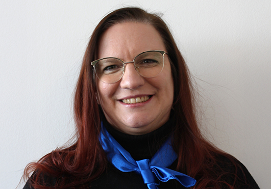 Frau lächelt mit Brille und blauem Halstuch