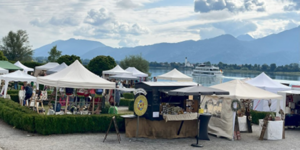 Marktstände am See vor Bergkulisse